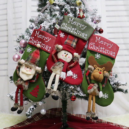 Three Christmas stockings with festive designs hanging on a decorated tree.